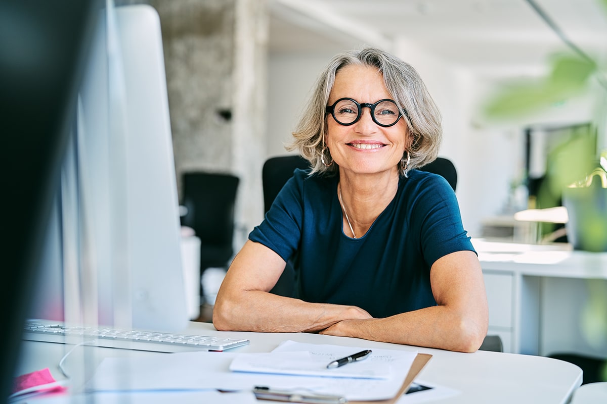 Woman smiling sitting at a desk in front of a computer