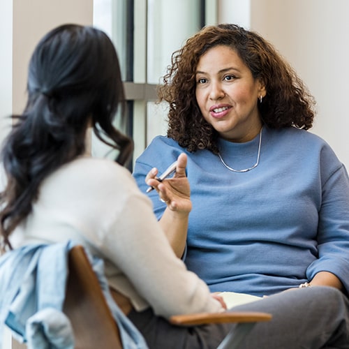 An unrecognizable patient listens as her mature adult female therapist gives her some straightforward advice.