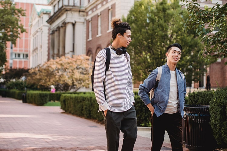 Two young men walking among old campus buildings