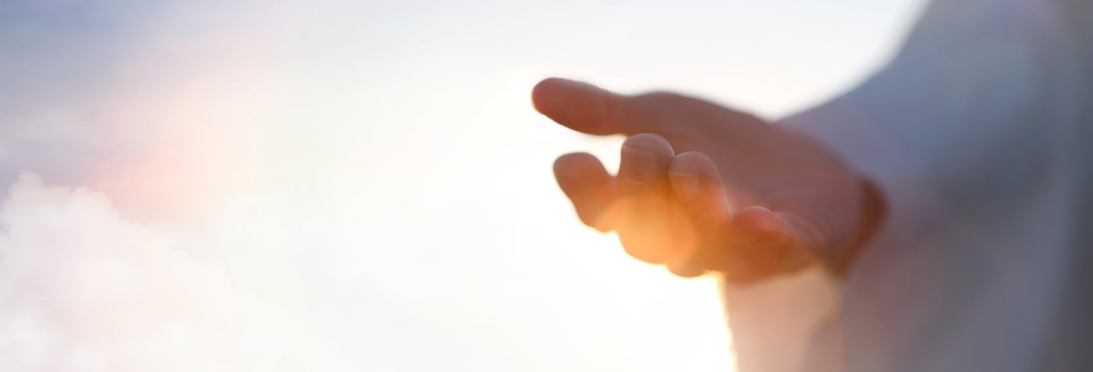 A hand reaching out with clouds in the background