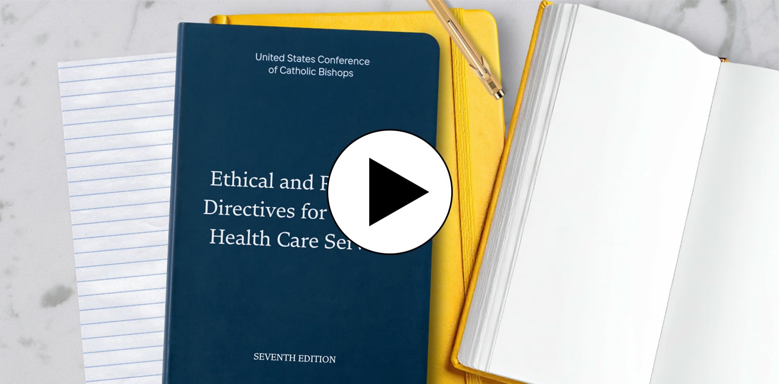 A blue book labeled United States Conference of Catholic Bishops Ethical and Religious Directives for Catholic Health Care Services Seventh Edition and two yellow books on a granite surface